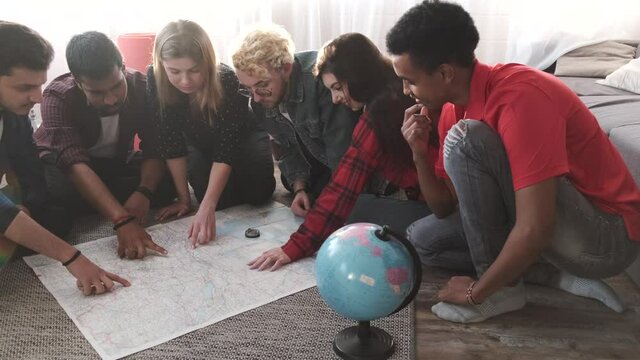 Group of diverse friends looking at map in the bright room