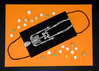 Medical black mask, human skeleton, pills on an orange background. Concept of Halloween, addiction, drug addiction, bad habits. Halloween layout.