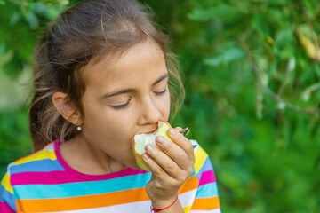 The child eats an apple in the garden. Selective focus.