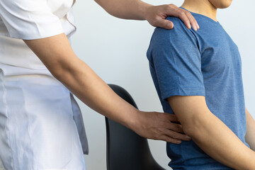 The doctor is diagnosing the patient's back pain. A male with back pain sees a doctor for treatment.