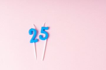 Festive blue number 25 candles. Pink background. Space for text. Birthday conception