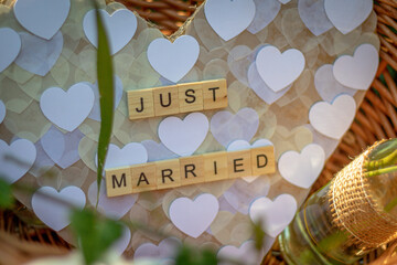 a heart with the words Just married made of single wooden letters in a basket as decoration at wedding celebration - obrazy, fototapety, plakaty