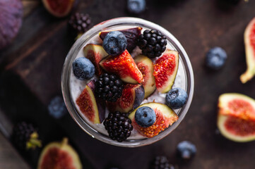 Healthy chia pudding with figs and dark berries in glass on the rustic background. Selective focus. Shallow depth of field.
