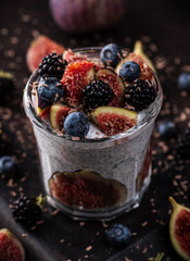 Healthy chia pudding with figs and dark berries in glass on the rustic background. Selective focus. Shallow depth of field.
