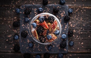 Healthy chia pudding with figs and dark berries in glass on the rustic background. Selective focus. Shallow depth of field.
