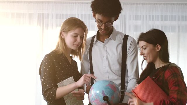 Multi ethnic friends looking at globe at home