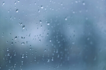 rain drops during raining in rainy day outside window glass with blurred background with water droplet flow down the surface