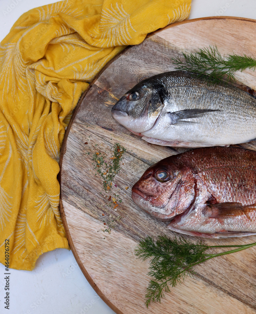 Wall mural raw gilt-head bream of two different types on a table. fresh fish on cutting board. eating fresh con