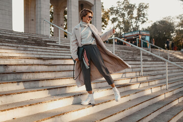 stylish fashionable woman walking in street in elegant style coat