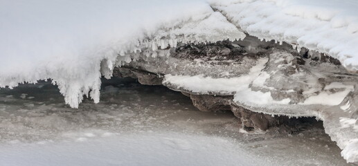Icicles and frost on a snow-covered frozen river