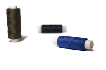 Three spools of thread of different colors isolated on white background 