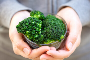 Bowl with cooked broccoli in woman hands