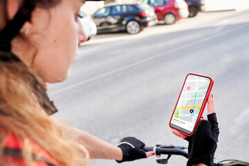 A cyclist delivery girl checks the address of her next shipment with her mobile phone