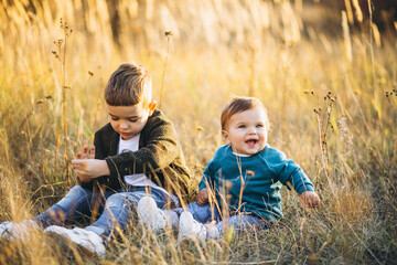Two little baby brothers sitting together in field