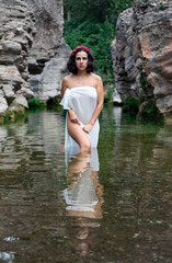 Fototapeta premium young woman dressed only in a white cloth reflected in the river water looking at camera