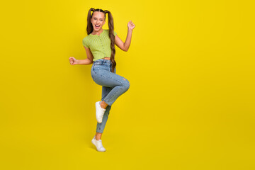 Fototapeta na wymiar Full length body size view of attractive cheerful long-haired girl dancing rejoicing isolated over bright yellow color background