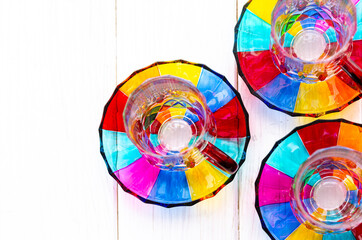 Fototapeta premium Multi-colored glass cups and saucers for coffee and tea stand on a wooden tray