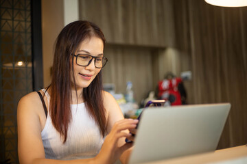 40 years old woman use phone and computer work at home.