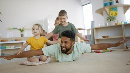 Group of small nursery school children with man teacher in classroom, playing.