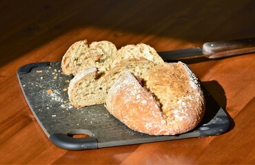 bread on a black board and a knife on a wooden table