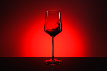 A splash of wine in a glass on a red background.