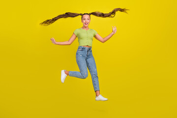 Full length body size view of attractive cheerful girl jumping having fun hair flying isolated over bright yellow color background