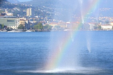 Naklejka na ściany i meble rainbow near the fountain over the lake near the city of lugano switzerland