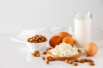 Protein food on a white background - cottage cheese, eggs, nuts. A set of healthy foods for a balanced diet.