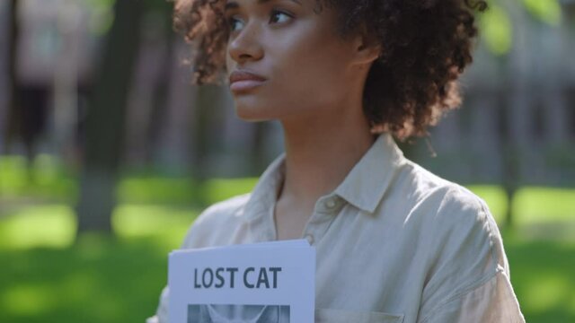 Young sad woman holding missing cat poster, owner looking for missing pet