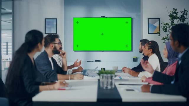 Multi-Ethnic Office Conference Room Meeting: Diverse Team of Successful Managers, Executives Talk, Use Green Screen Chroma Key TV. Businesspeople Investing in eCommerce Startup. Wide Static Shot