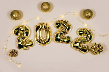 Golden 2022 balloons, gift, balls isolated on grey background. Helium balloons, gold foil numbers. Numbers for Happy New Year 2022. Party decoration, celebration, carnival.