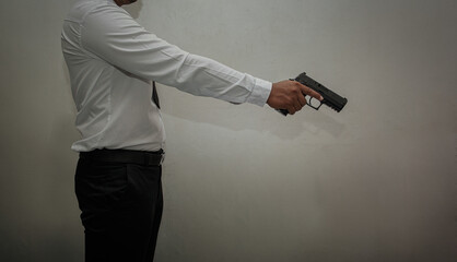 The murderer, a man in a white shirt and black pants, thrusts his pistol at his target. white background