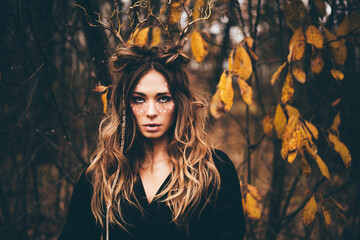 Woman with deer horns in autumn forest. Halloween concept.