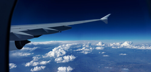 Wolkenpanorama mit A380 Flugzeugflügel vor blauschwarzem Horizont - obrazy, fototapety, plakaty