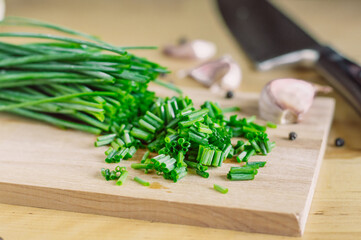 chropped green onions on a wooden board and garlic, bread,pepper and knife