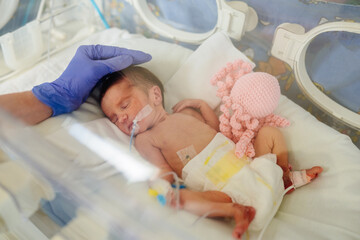 Premature newborn girl in hospital incubator after section at 33 weeks. Cute newborn baby inside...