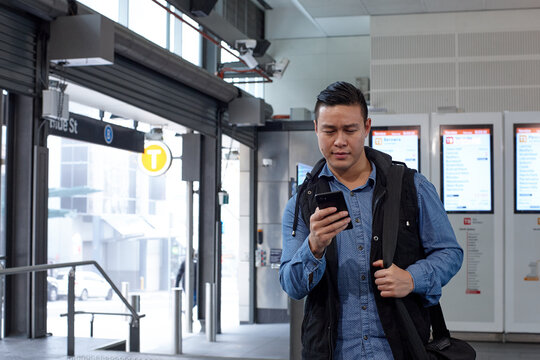 Young Asian man checking mobile device at train station