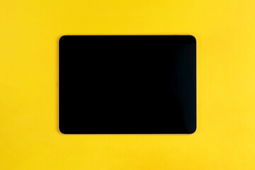 Black digital tablet on yellow background