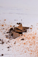 Pieces of black chocolate with cinnamon on white background