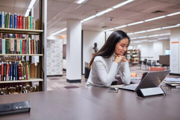 Young female Asian student working on her laptop at university library