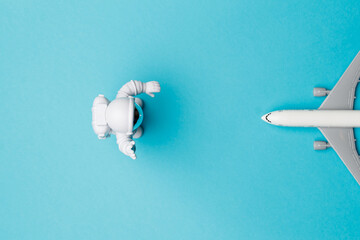 The concept of space tourism. The astronaut's toy directs the plane on a turquoise background. An astronaut sends tourists into space. Top view. Close-up. A place to copy. Free space