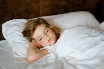 Obraz premium Cute little toddler girl sleeping in bed. Adorable baby child dreaming, healthy sleep of children by day. Deep sleeping of toddler. Kids resting.