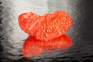 sliced mirrored grapefruit on black background