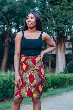 Beautiful African black woman walking in park. Beautiful young woman with brown skin. Strong black woman with wearing print skirt and turban.