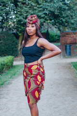 Beautiful African black woman walking in park. Beautiful young woman with brown skin. Strong black woman with wearing print skirt and turban.