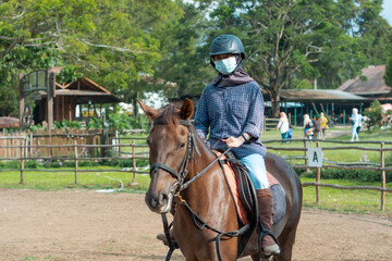 Women with mask and hijab learns to ride a horse. girls riding horses at the ranch. equestrian sport during the pandemic