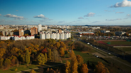 Flight over the autumn park. On the horizon there is a city houses.  Trees with yellow autumn leaves are visible.  Aerial photography.