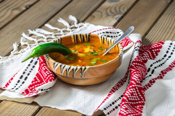 Romanian traditional beef soup served in clay bowl on traditional towel. In romanian is called 