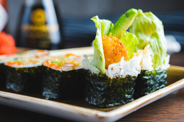 Traditional Japanese rolls with shrimps and vegetables on a plate with wooden chopsticks