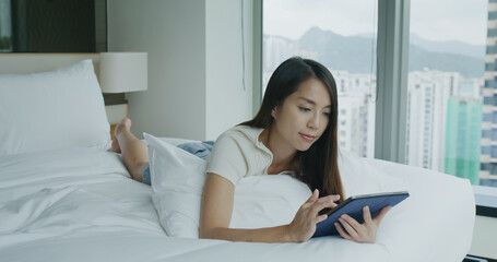 Woman use of tablet computer and lying on bed